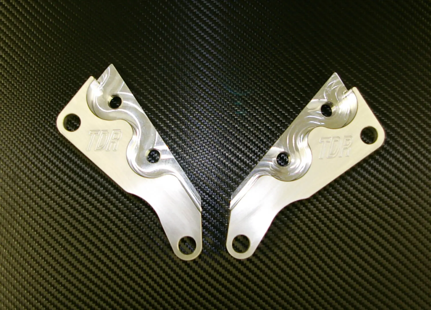 A pair of silver metal parts on top of a black surface.