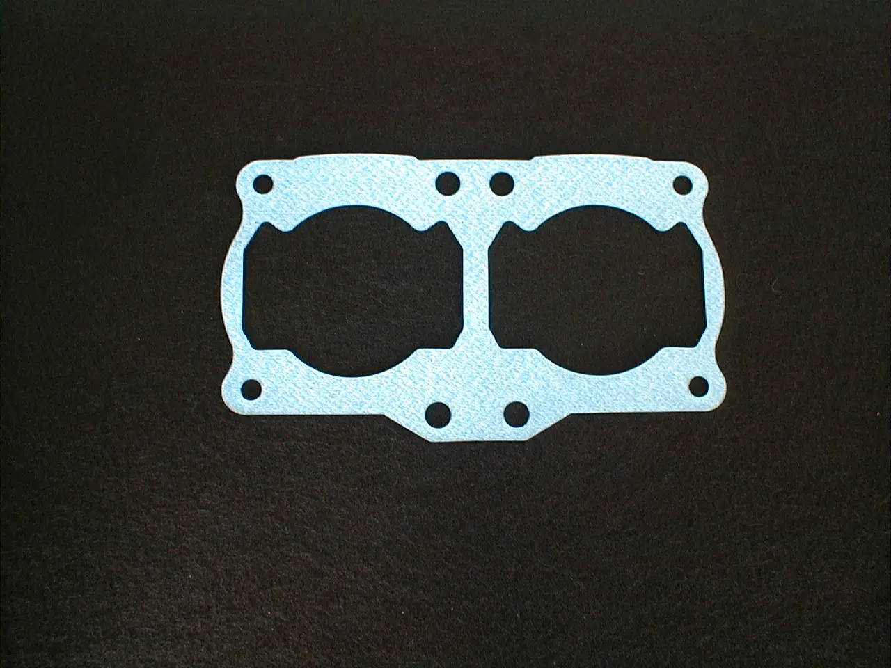 A blue gasket on a black surface, specifically the 1 Piece RZ 350/Banshee base gasket with part number 15-5701.