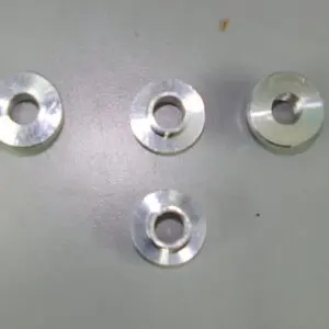 Four stainless steel washers and TDR billet front shock bushings (Part# 17-5780) on a table.