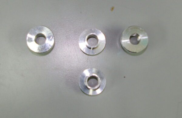 Four stainless steel washers and TDR billet front shock bushings (Part# 17-5780) on a table.