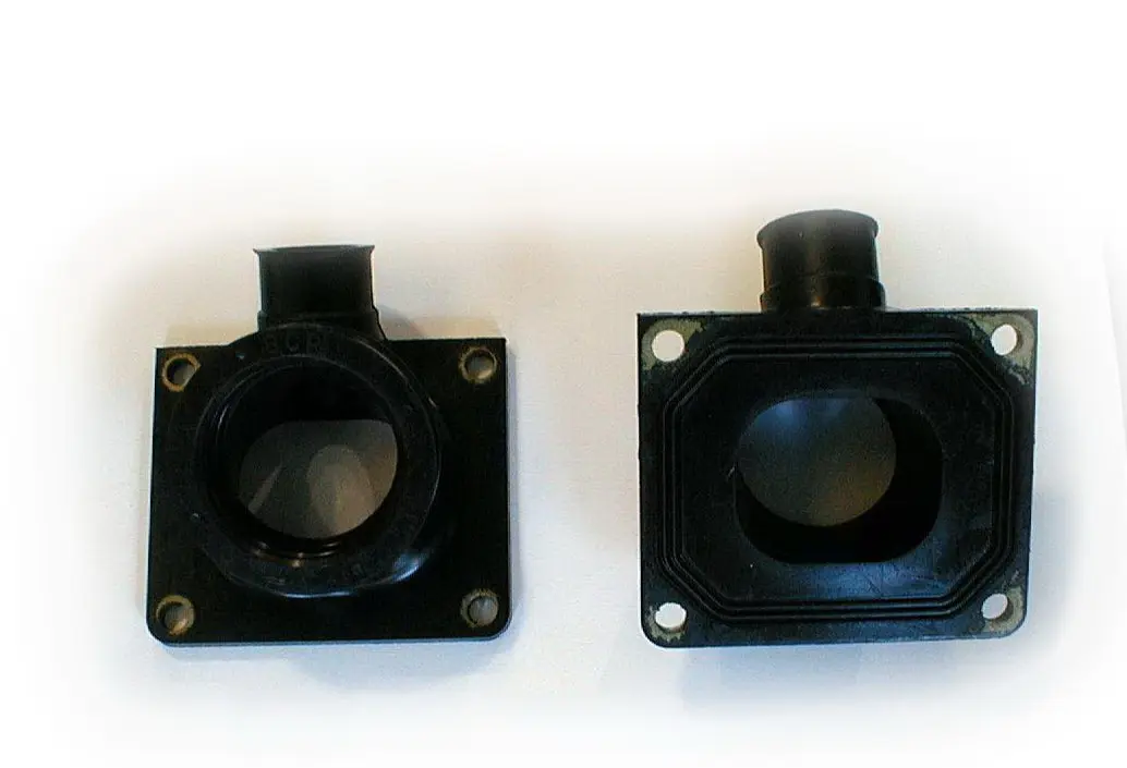 Two black plastic pipe fittings on a white surface beside a WSM Intake Manifold for stock 28mm carburetor, Part# 22-5824.