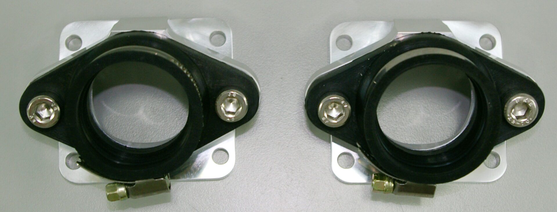 A pair of Chariot Billet intake manifold single style brackets on a white surface.