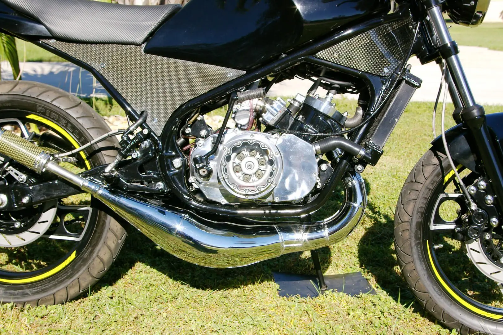 A motorcycle is parked on the grass near a fence.