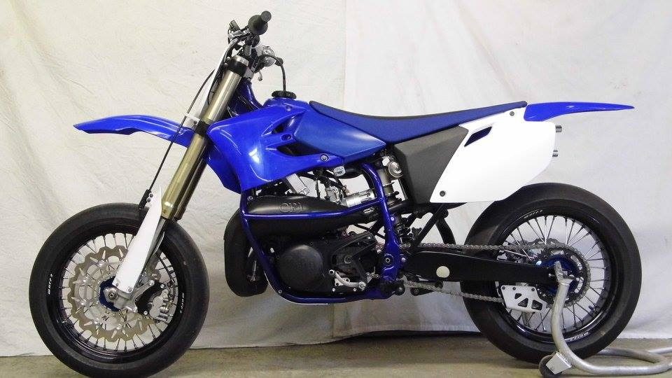 A blue and white dirt bike parked in a garage.