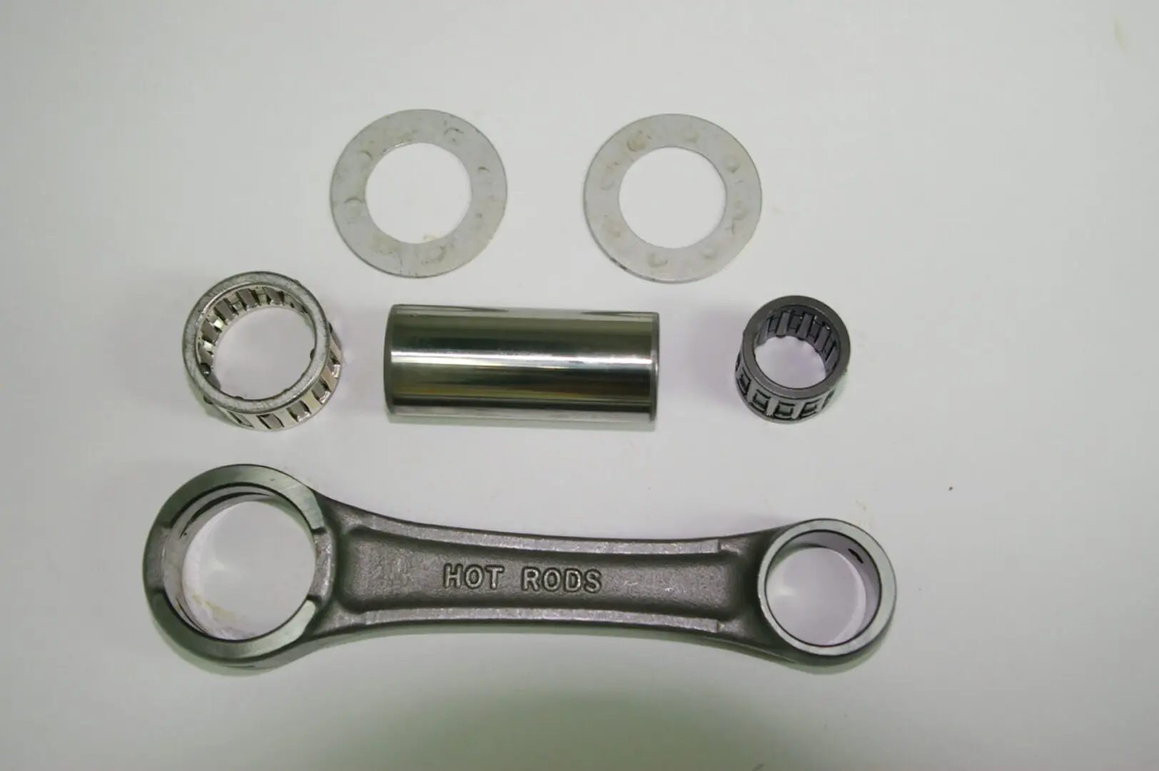 A set of metal parts including a sprocket and HOT RODS Connecting Rod Stock 110mm length, Part# 91-5715.