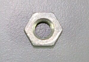 An OEM Banshee Chain adjuster nut rests on a gray surface.