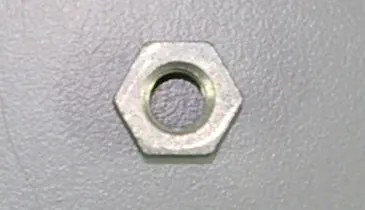 An OEM Banshee Chain adjuster nut rests on a gray surface.