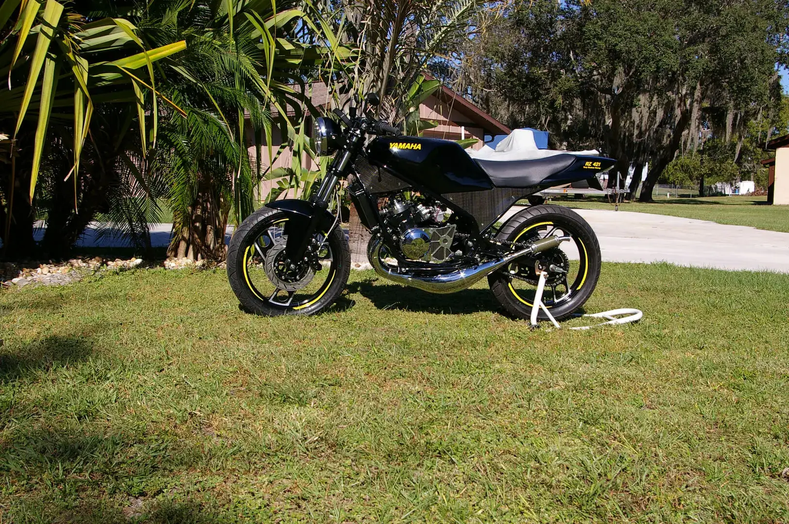 A motorcycle parked in the grass near some trees.